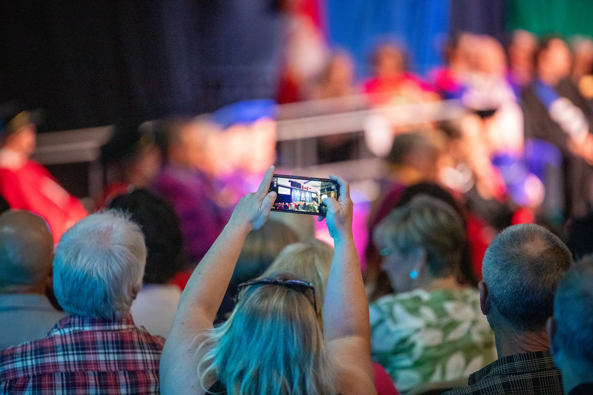 A person holding up a smartphone to record the stage.