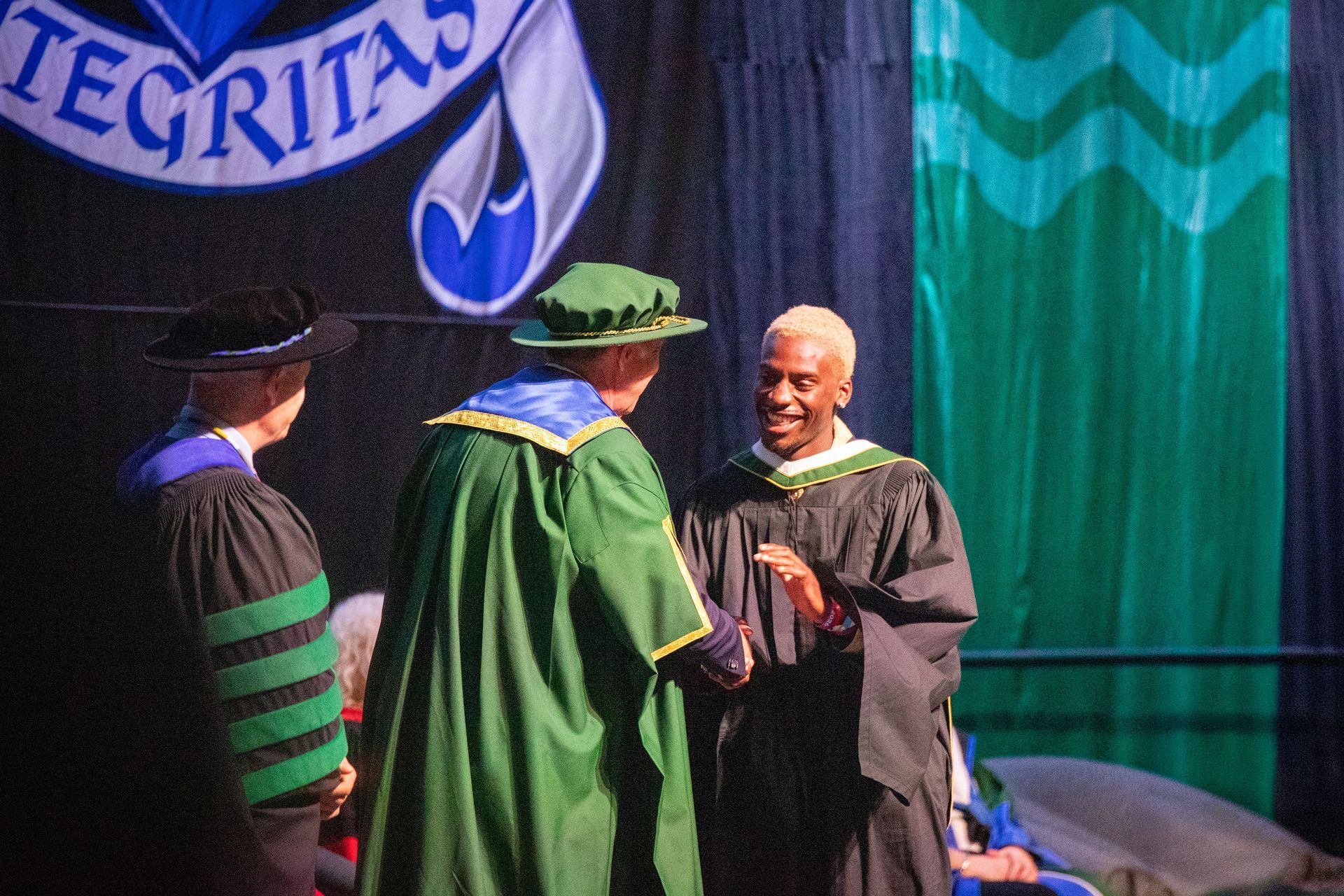 Graduation ceremony with a smiling graduate on stage
