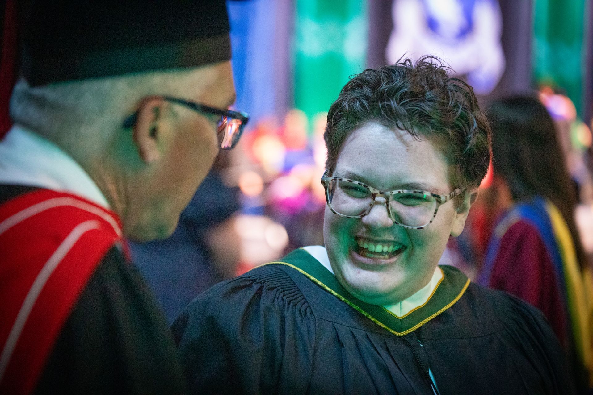 Two smiling people talking at a ceremony