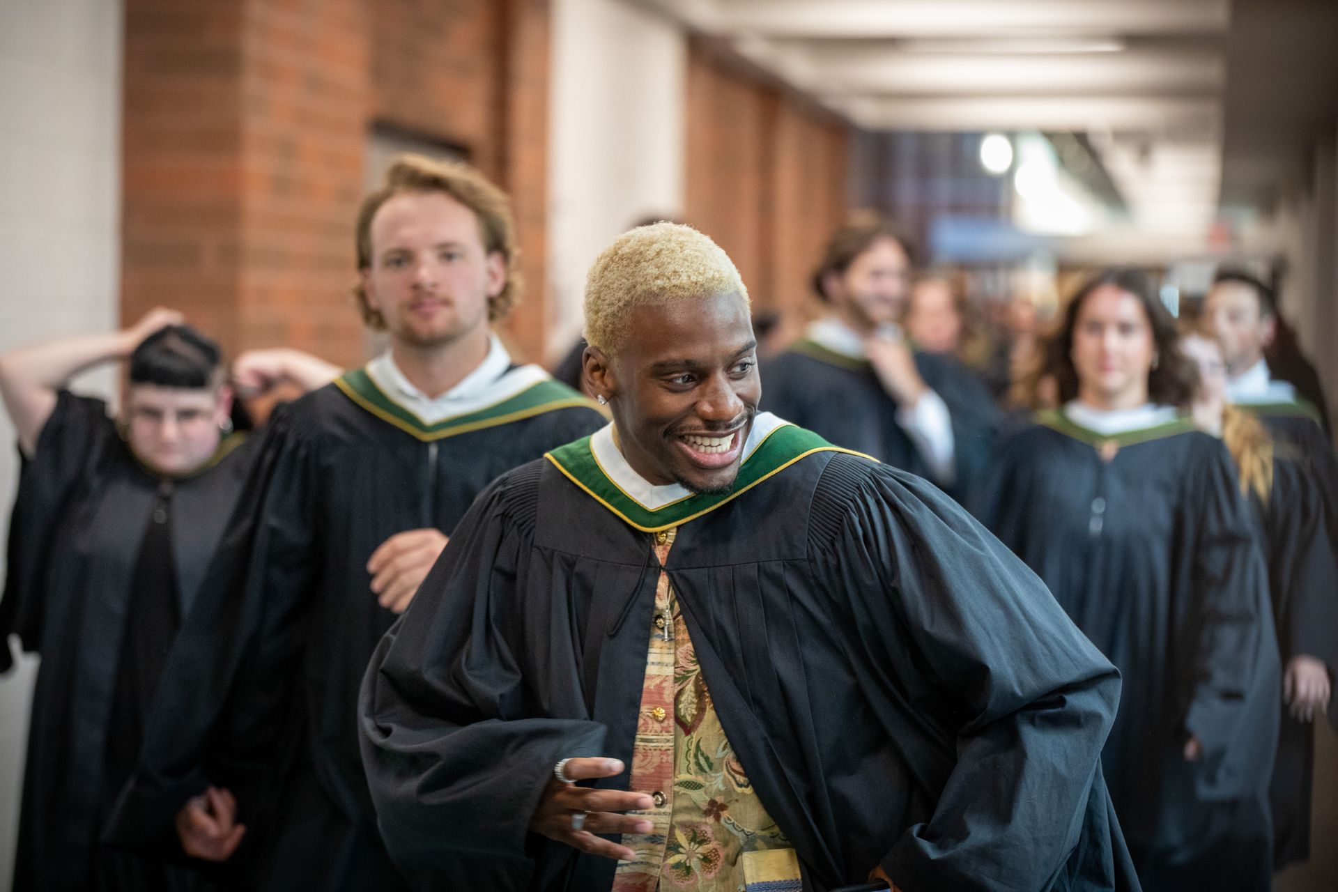 Graduates in black gowns walking down a hallway after a ceremony