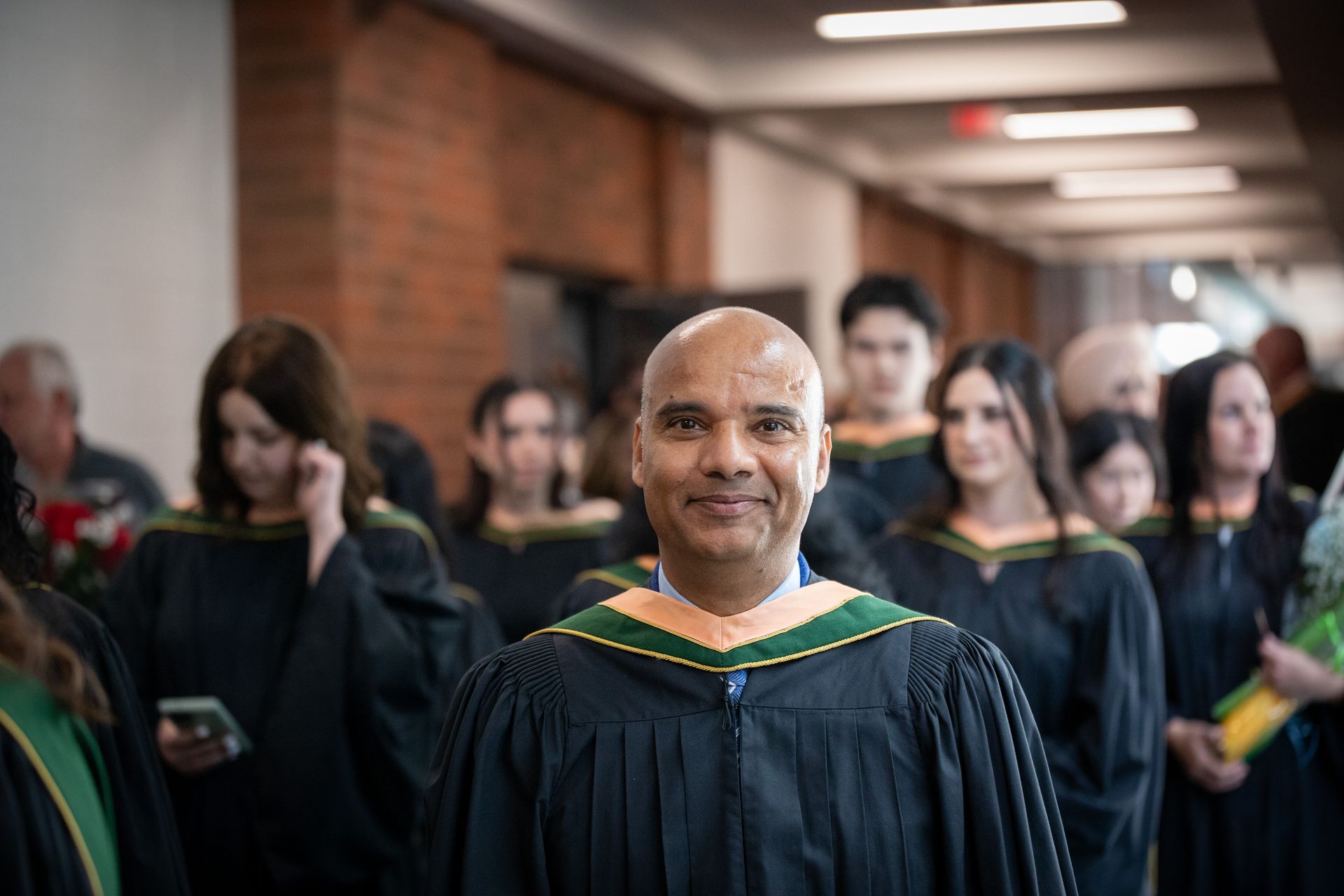 Graduation ceremony with a smiling graduate in a gown in front of other graduates