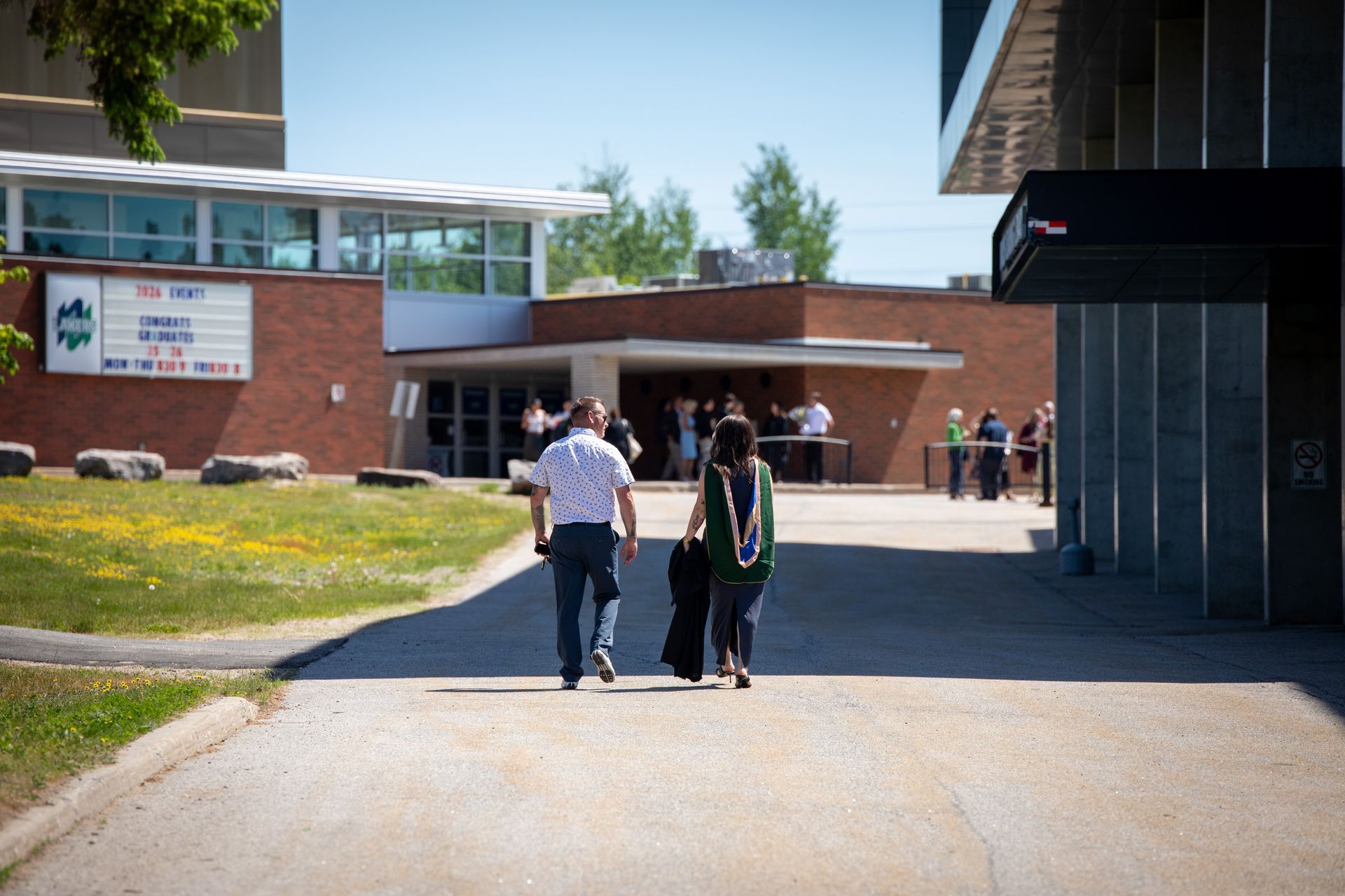 People walking toward a school building on a sunny day