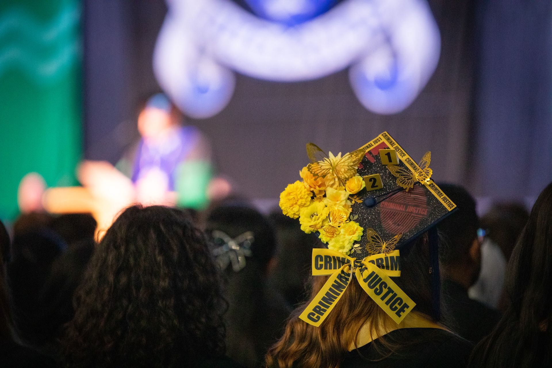 Yellow flowers and a black ribbon tribute at a blurred indoor event with stage lights