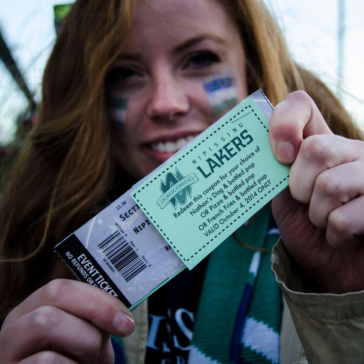 Woman holding two Lakers tickets close to the camera outdoors