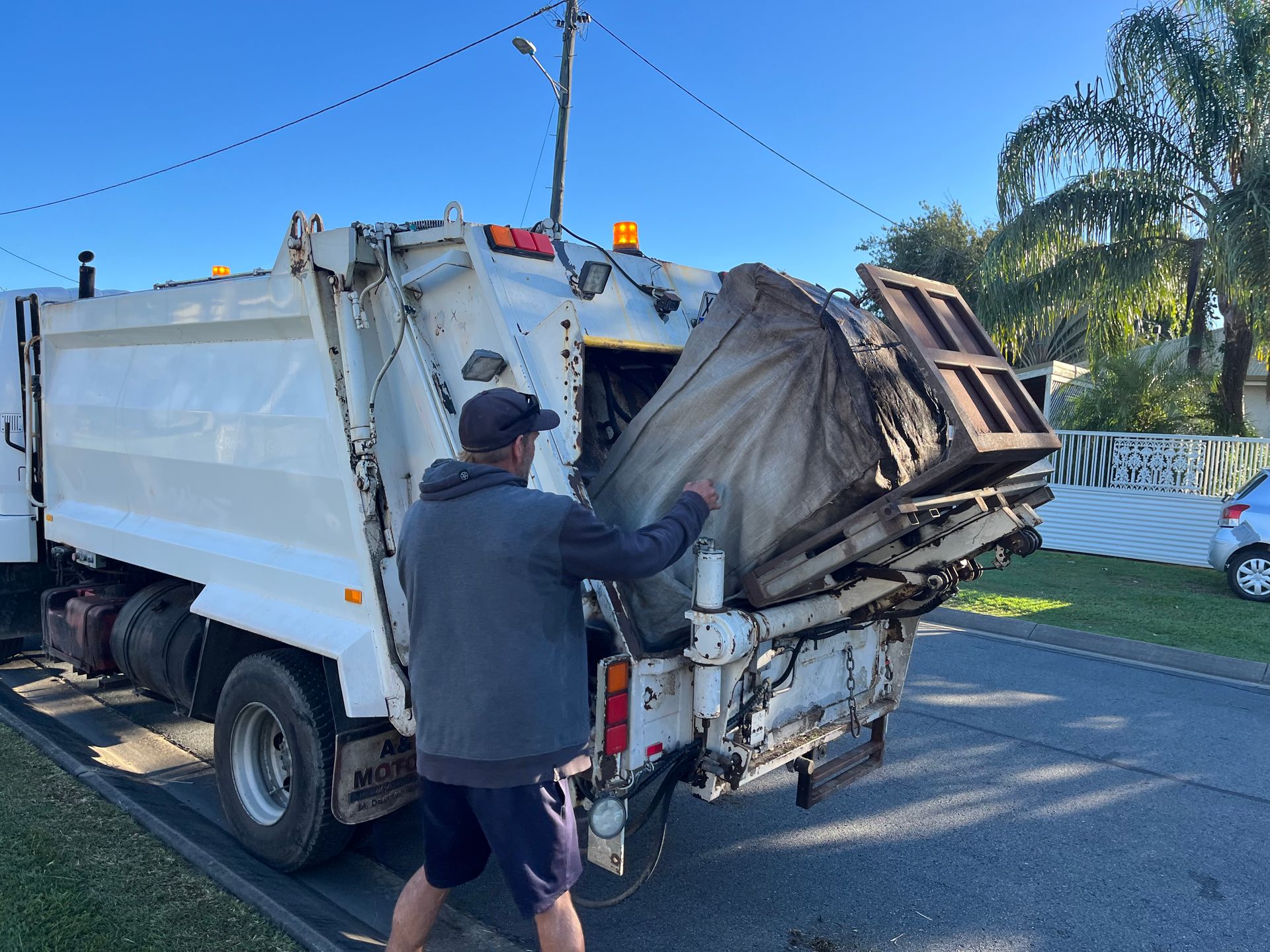 A Man Emptying A Bag Into A Rubbish Truck — Mackay Bags in Ooralea, QLD