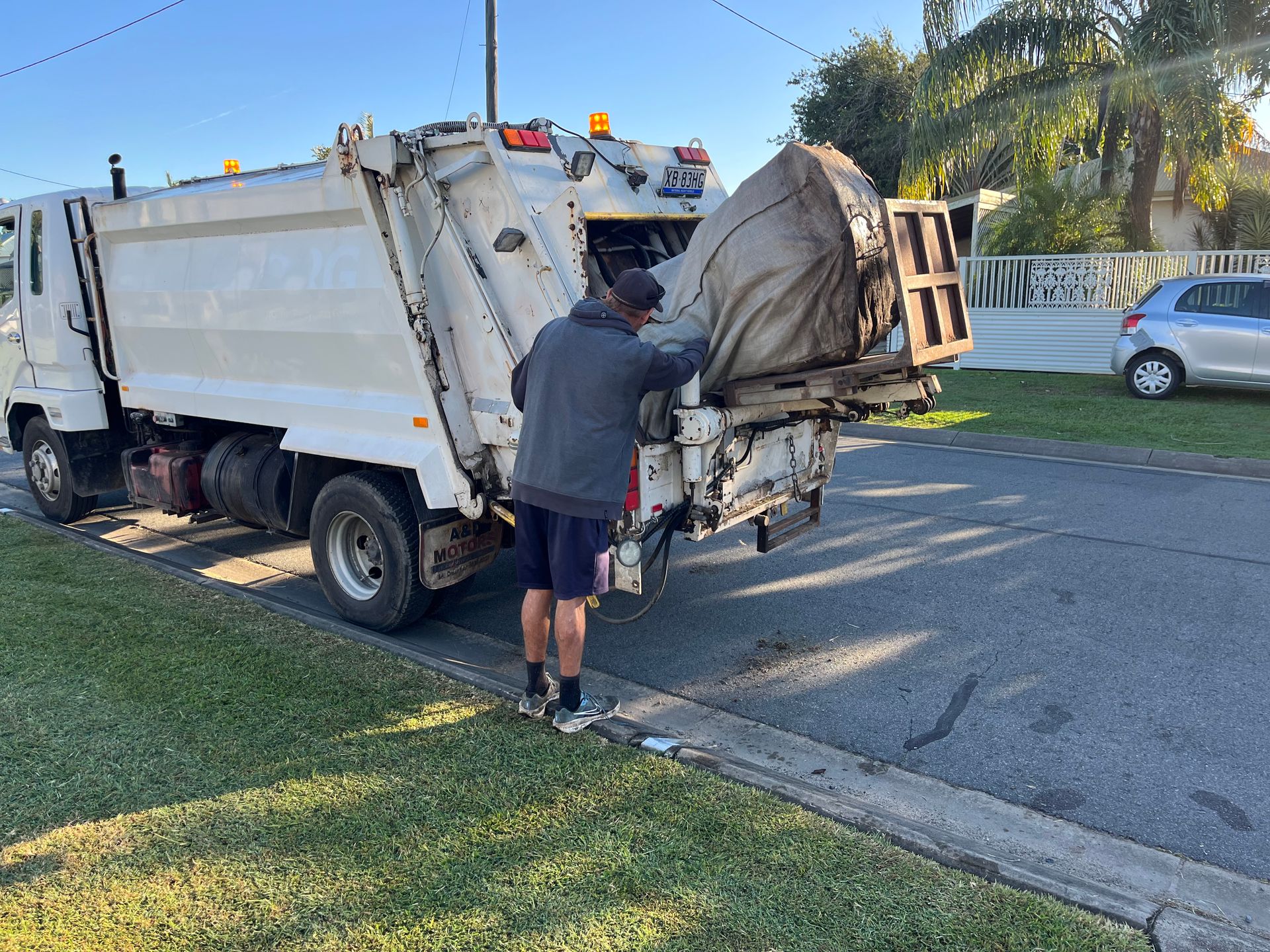 A Man Is Standing Next To Two Trash Cans In A Garden — Mackay Bags in East Mackay, QLD