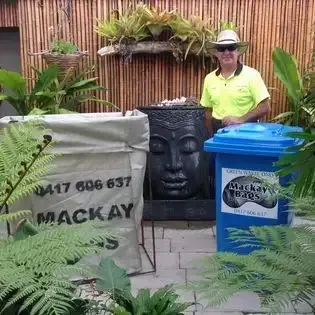A Yellow Dumpster Filled With Wood Is Parked In Front Of A Brick House — Mackay Bags in Rural View, QLD