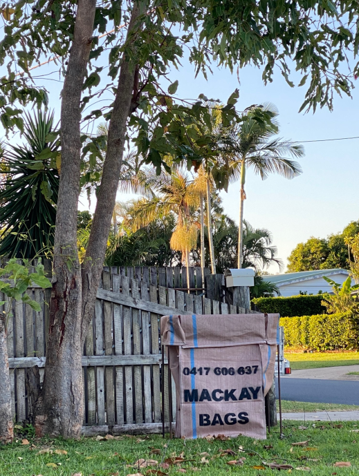 A blue trash can filled with plants is sitting next to a bunch of plants — Mackay Bags in East Mackay, QLD