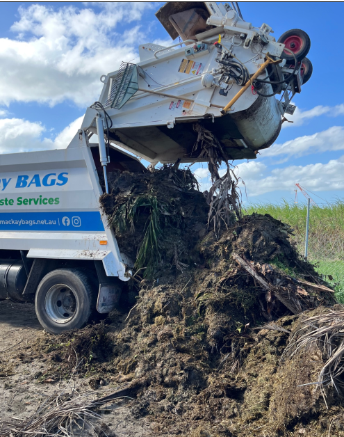 Green waste being emptied out of a garbage truck — Mackay Bags in East Mackay, QLD
