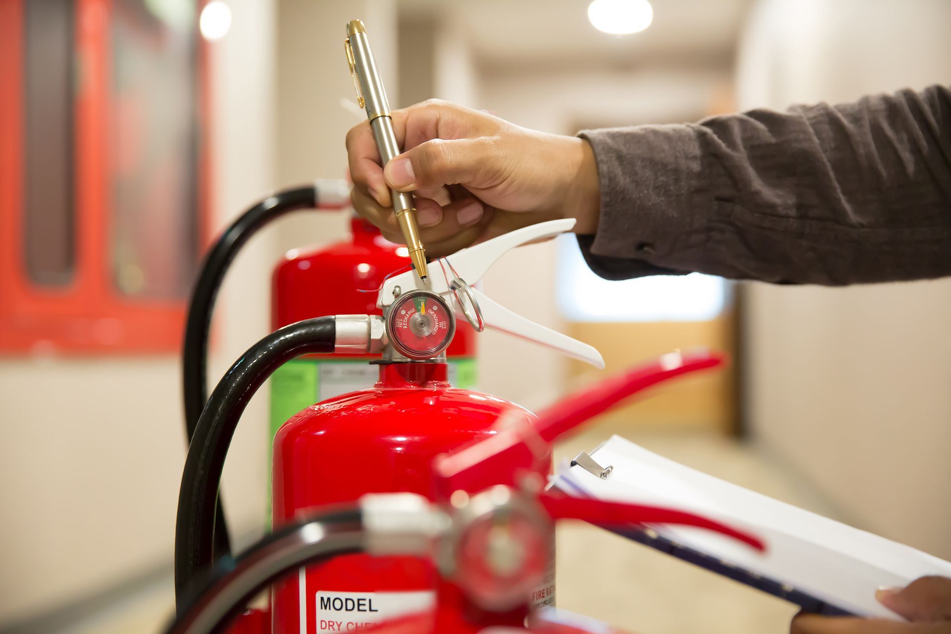 Technician inspecting and tagging a fire extinguisher during routine safety servicing check.