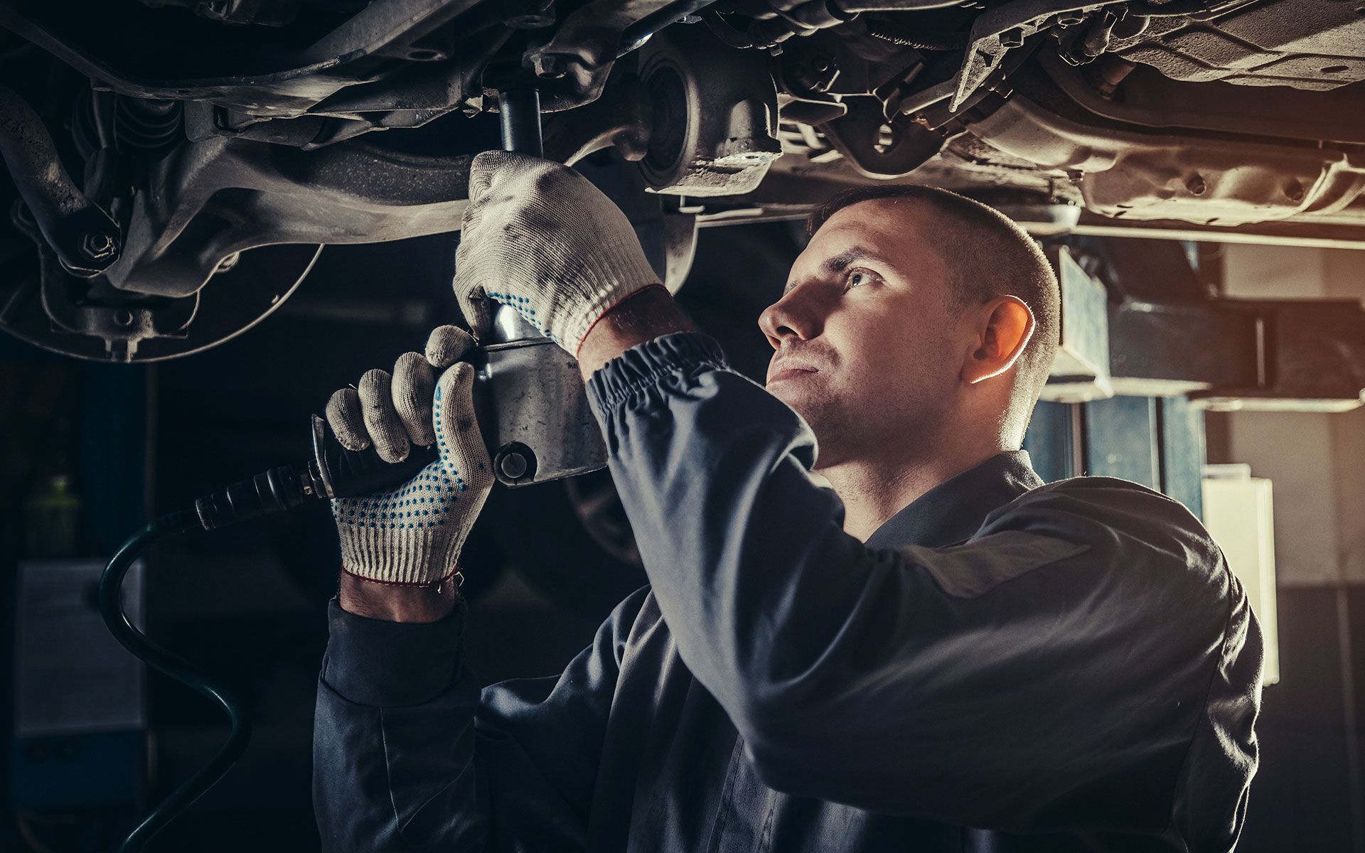 A man is working under a car with a wrench.