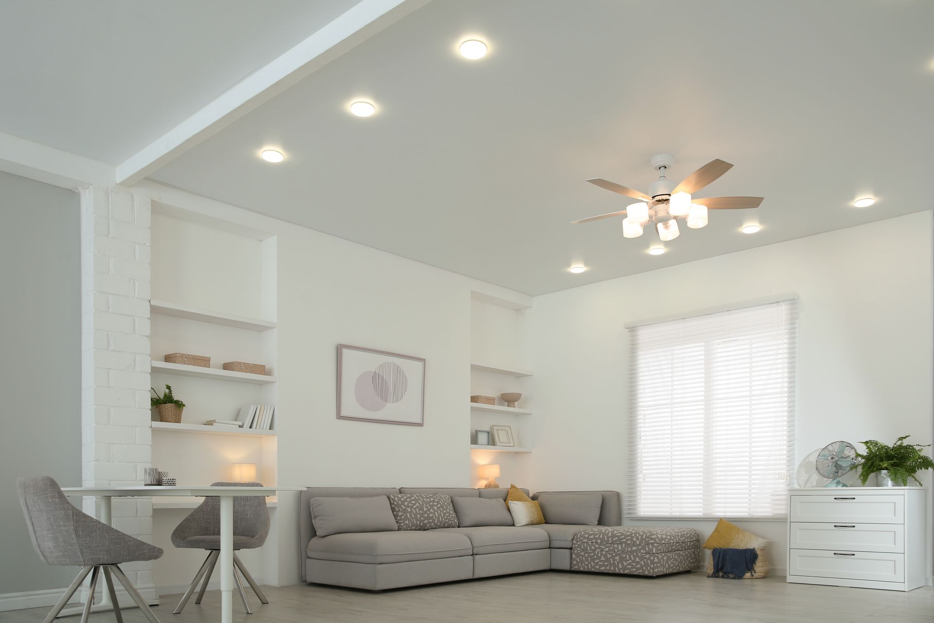 Bright white living room with recessed lights, sectional sofa, and built-in shelving.