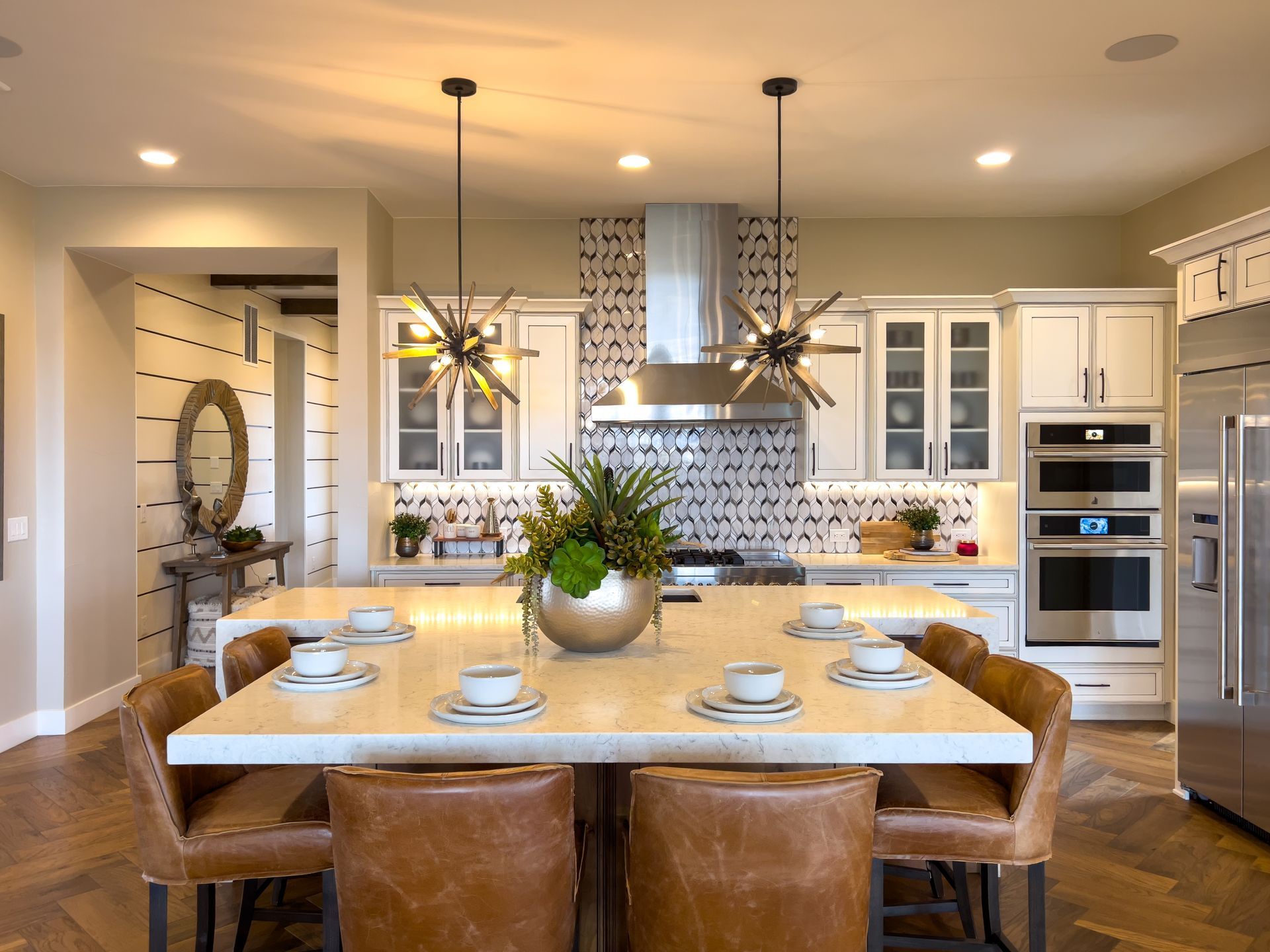 Modern kitchen with island seating, pendant lights, stainless steel appliances, and patterned backsplash.
