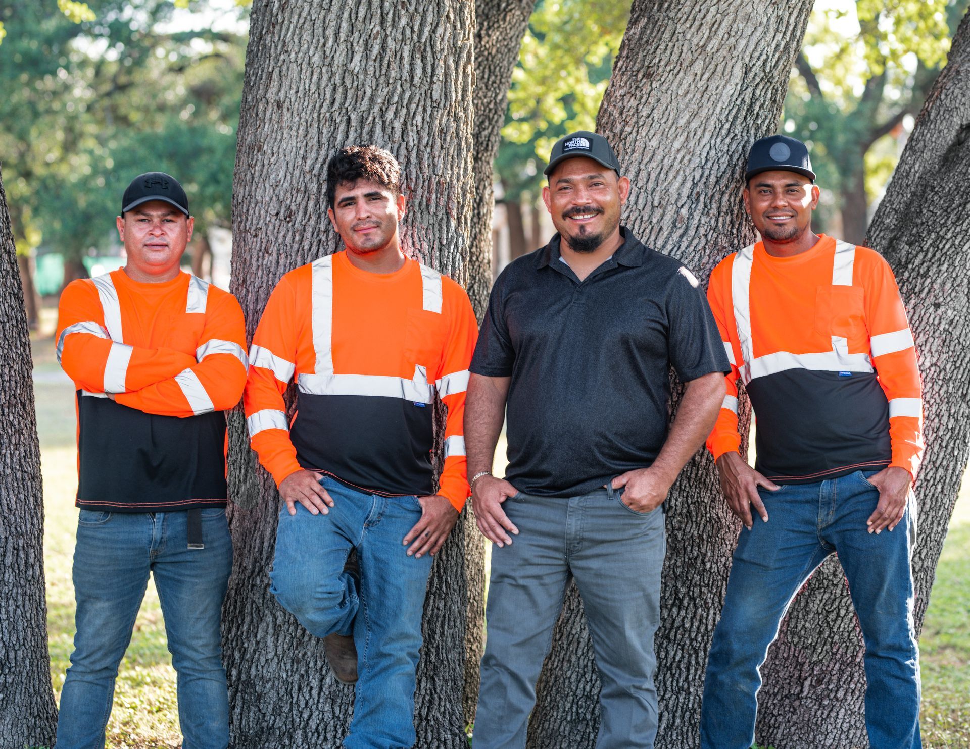 A group of men are posing for a picture in front of a tree.