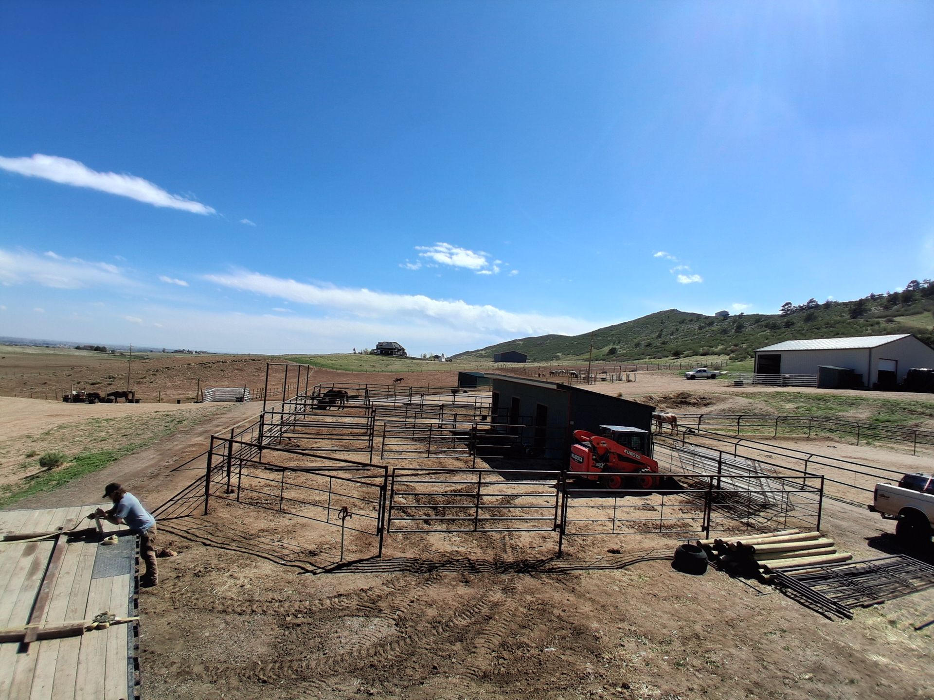 Rural corral with cattle pens and fencing under a clear blue sky on a dusty ranch landscape
