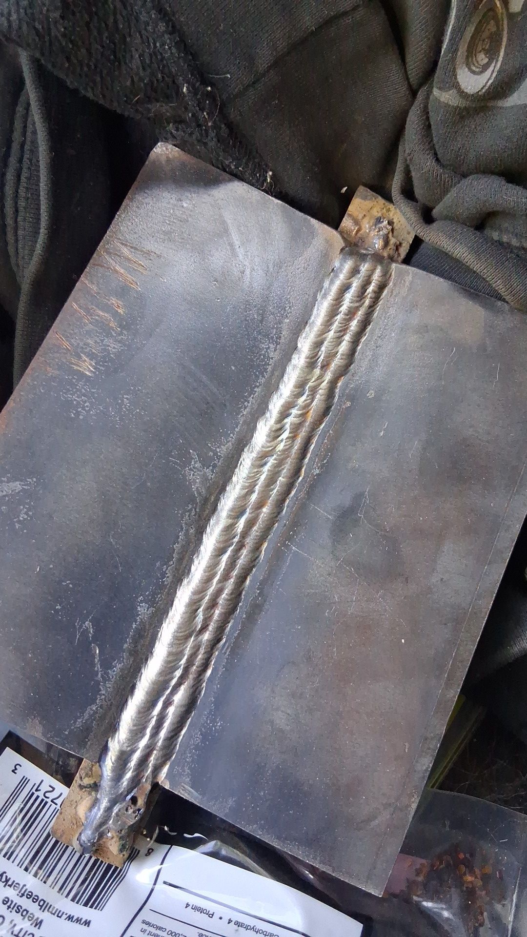 Close-up of a clear plastic bag containing several silver metallic rods or tools on a dark fabric surface