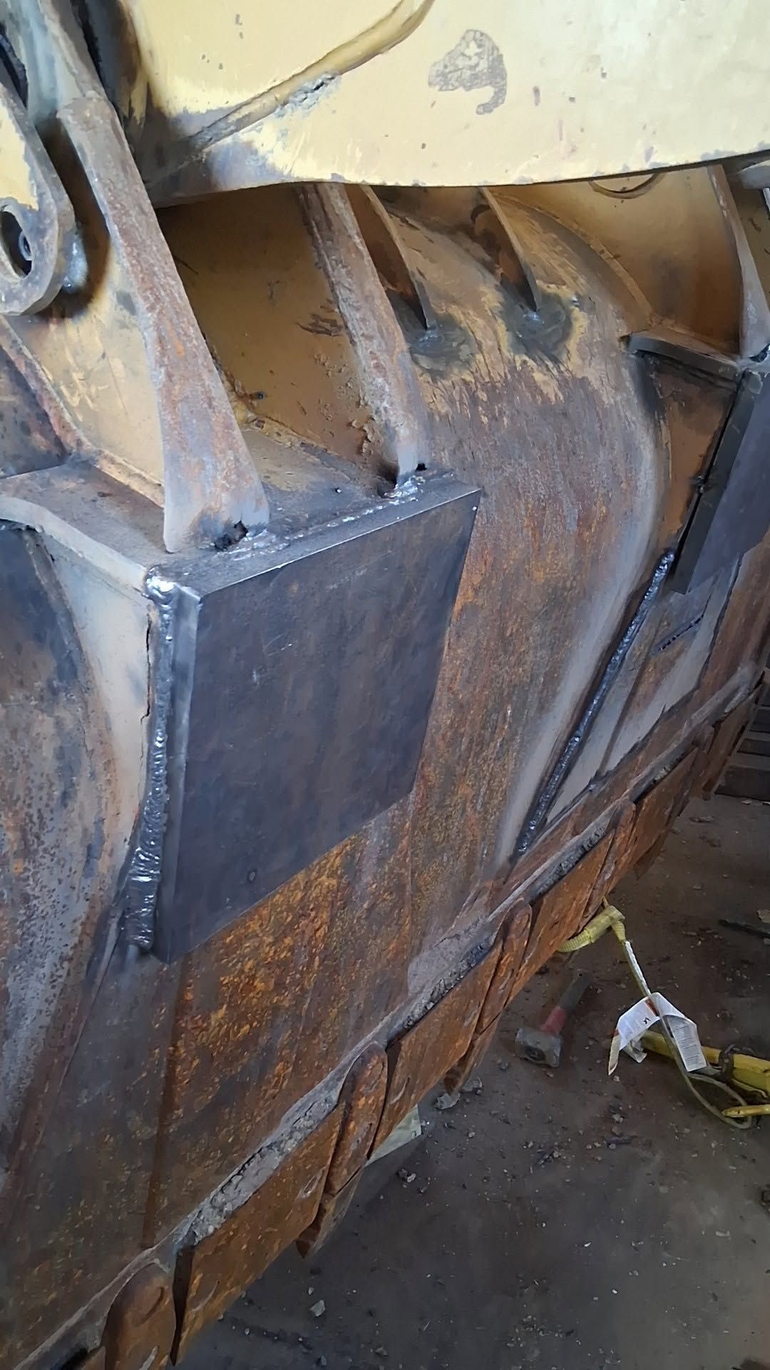 Close-up of a rusted metal machine part with bolts and worn brown panels outdoors