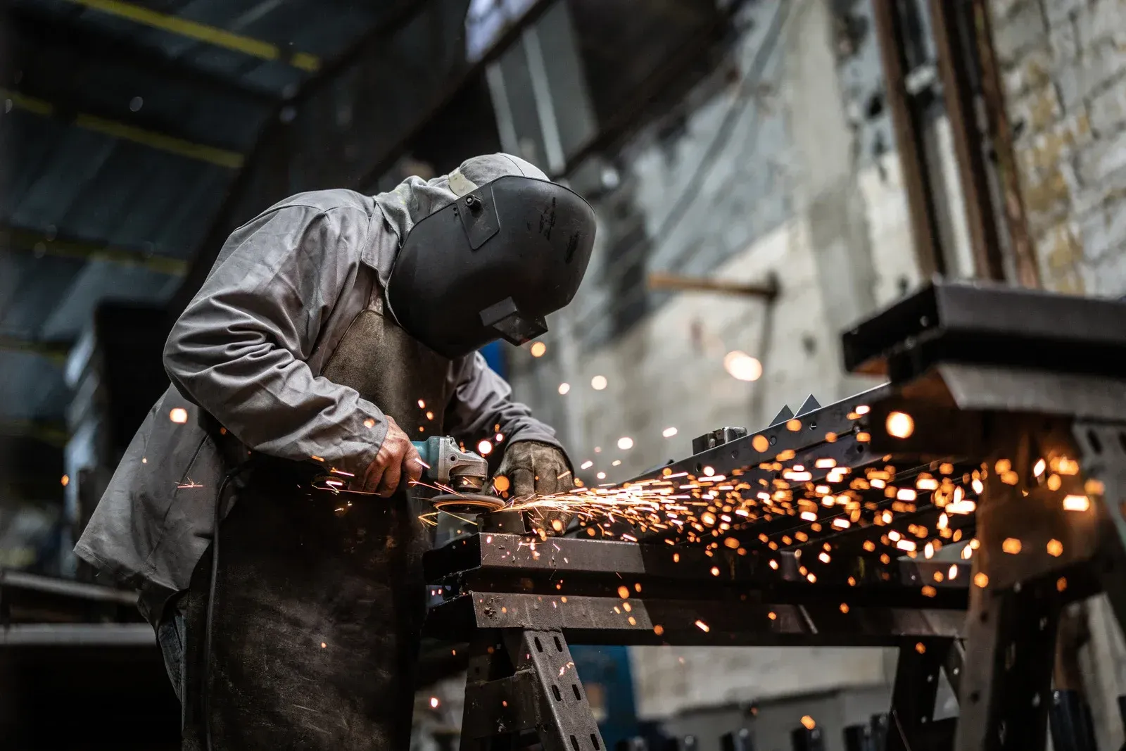 Worker grinding metal in a workshop, sending bright sparks across the frame.