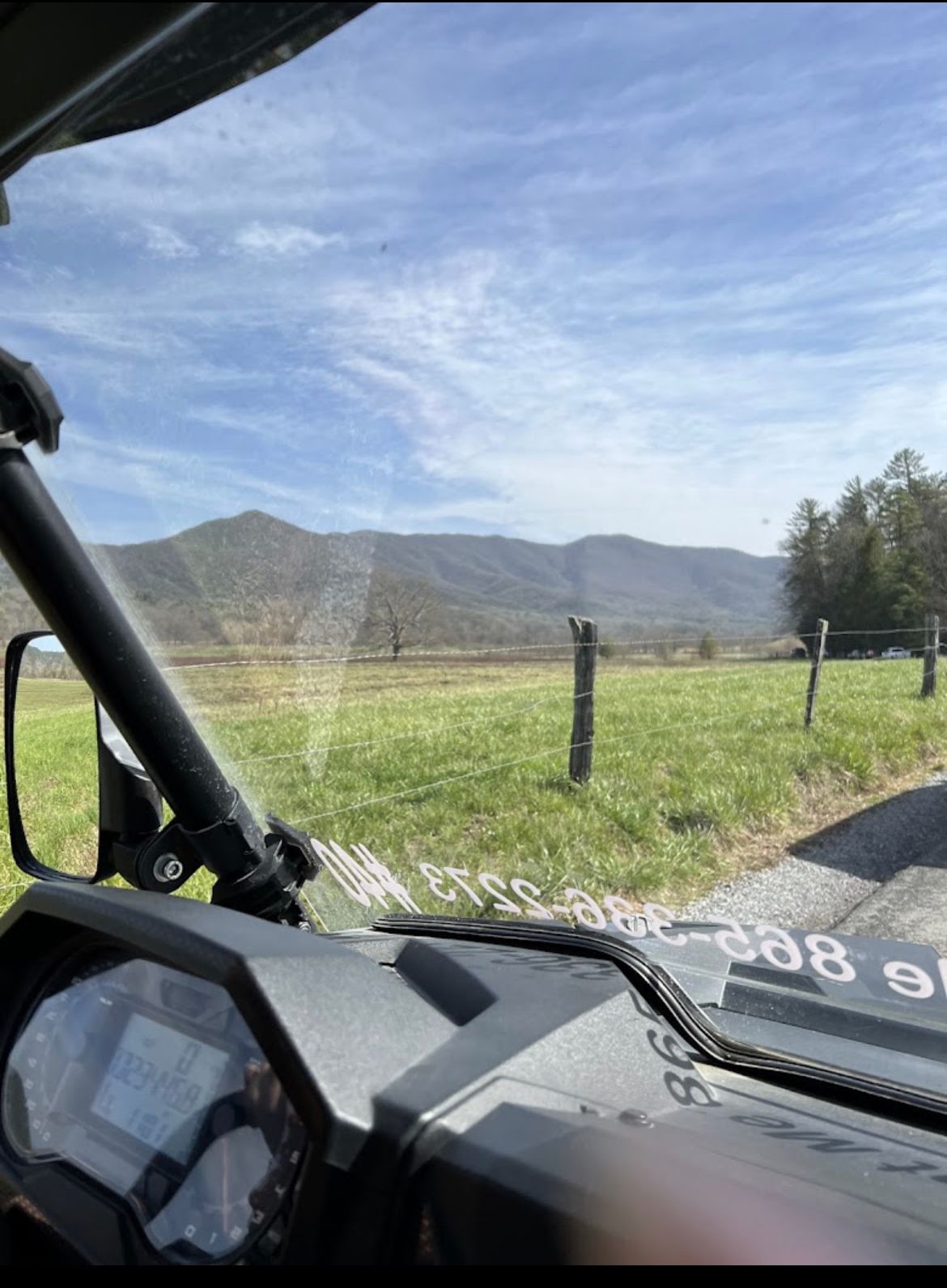 A view of a field from the inside of a vehicle.