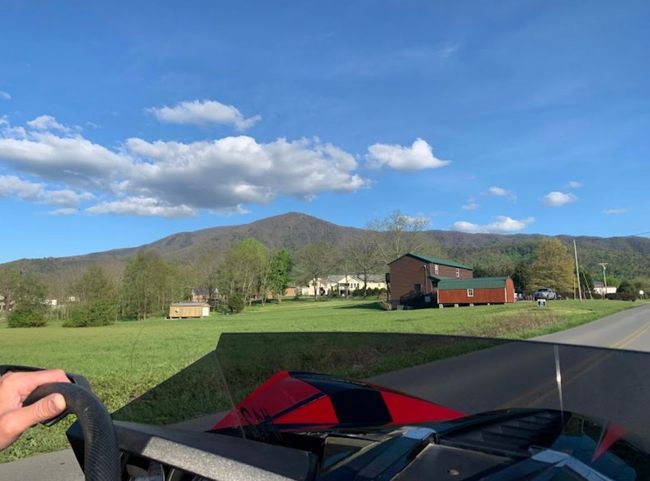 A person is driving a vehicle down a road with mountains in the background.