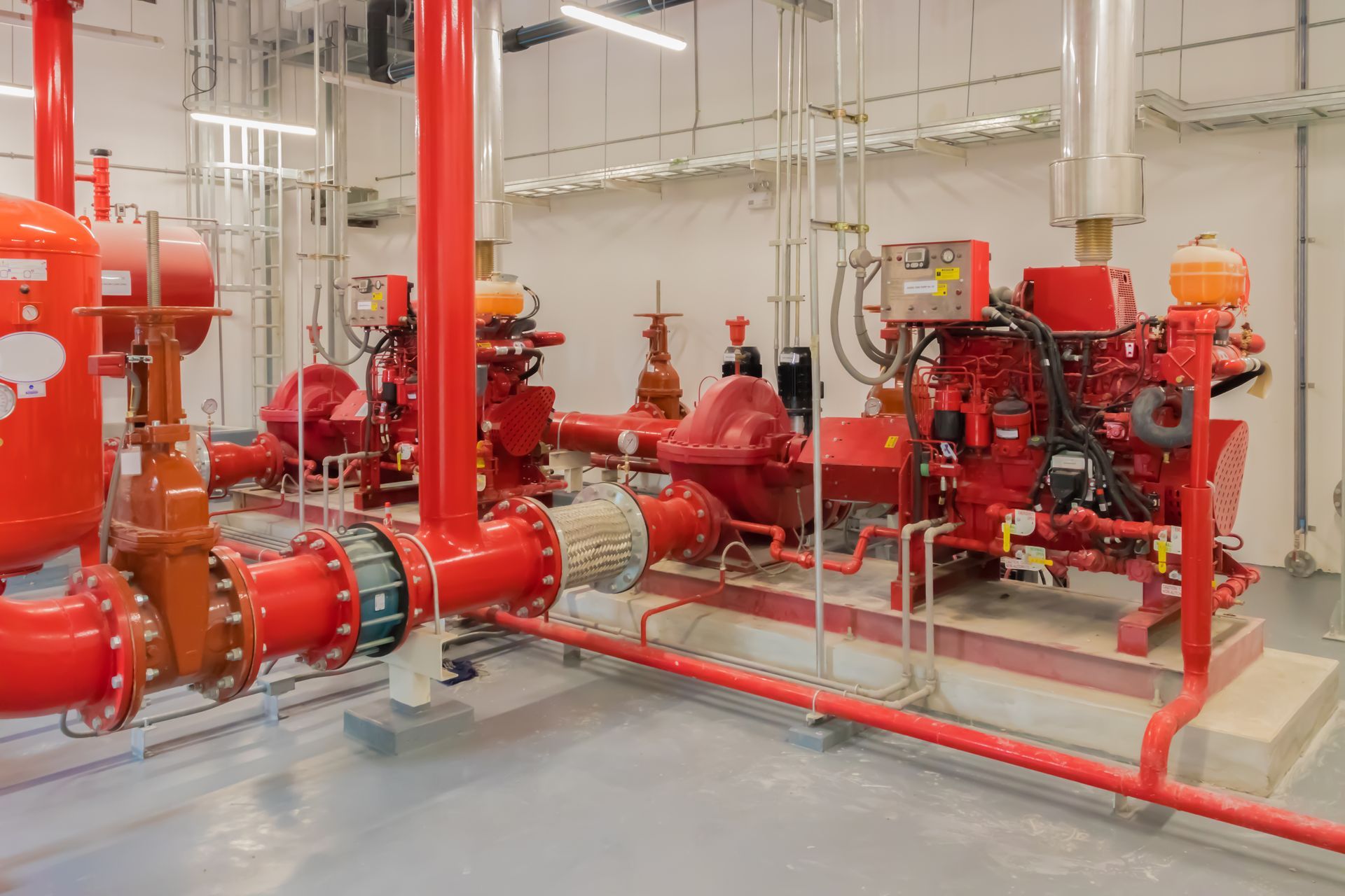Deux camions de pompiers rouges et leurs systèmes de tuyauterie associés sont installés dans une salle des machines stérile.