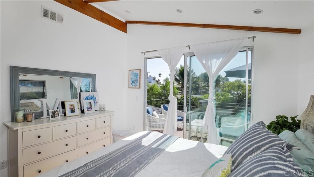 A bedroom with a large bed , dresser , mirror and sliding glass doors.