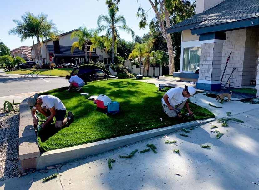 Three men are working on a lawn in front of a house. Remodeling services for the front yard.