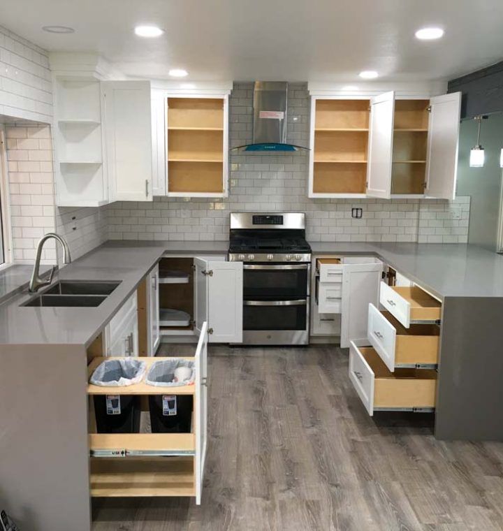 A kitchen with a sink stove and drawers open