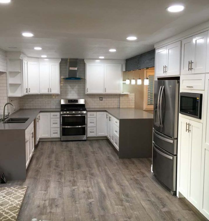 A kitchen with white cabinets , a stove , a refrigerator , and a sink.