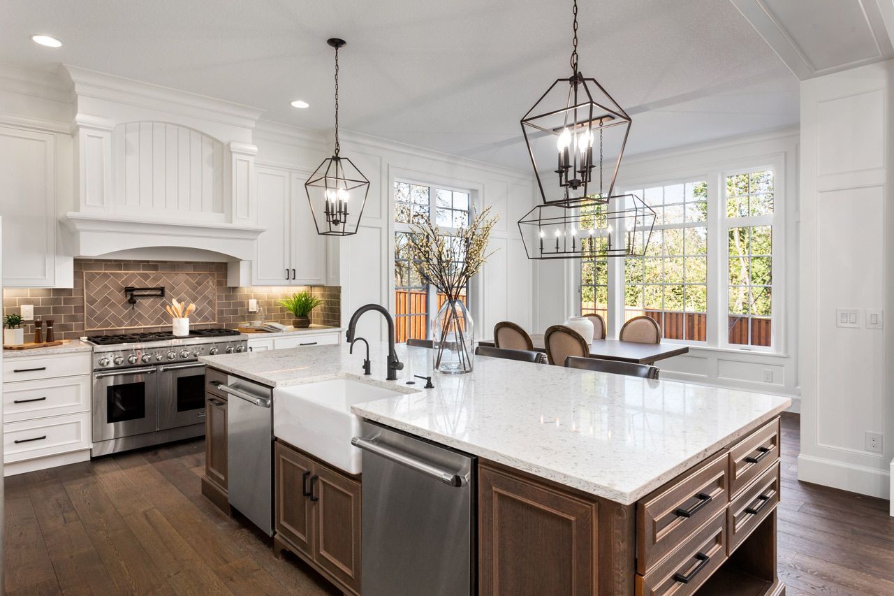 A kitchen with stainless steel appliances , a large island , a sink , and a dining room.