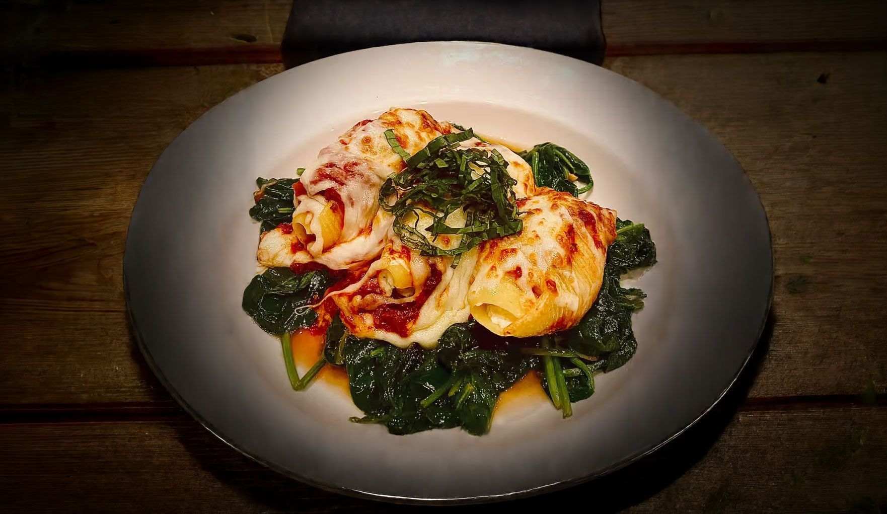 Plated pasta with red sauce and greens on a white dish