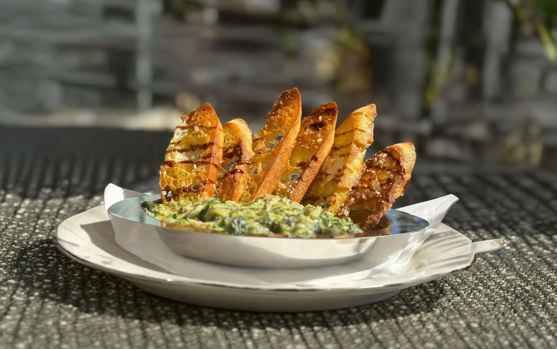 Artichoke dip with slices of toasted bread.