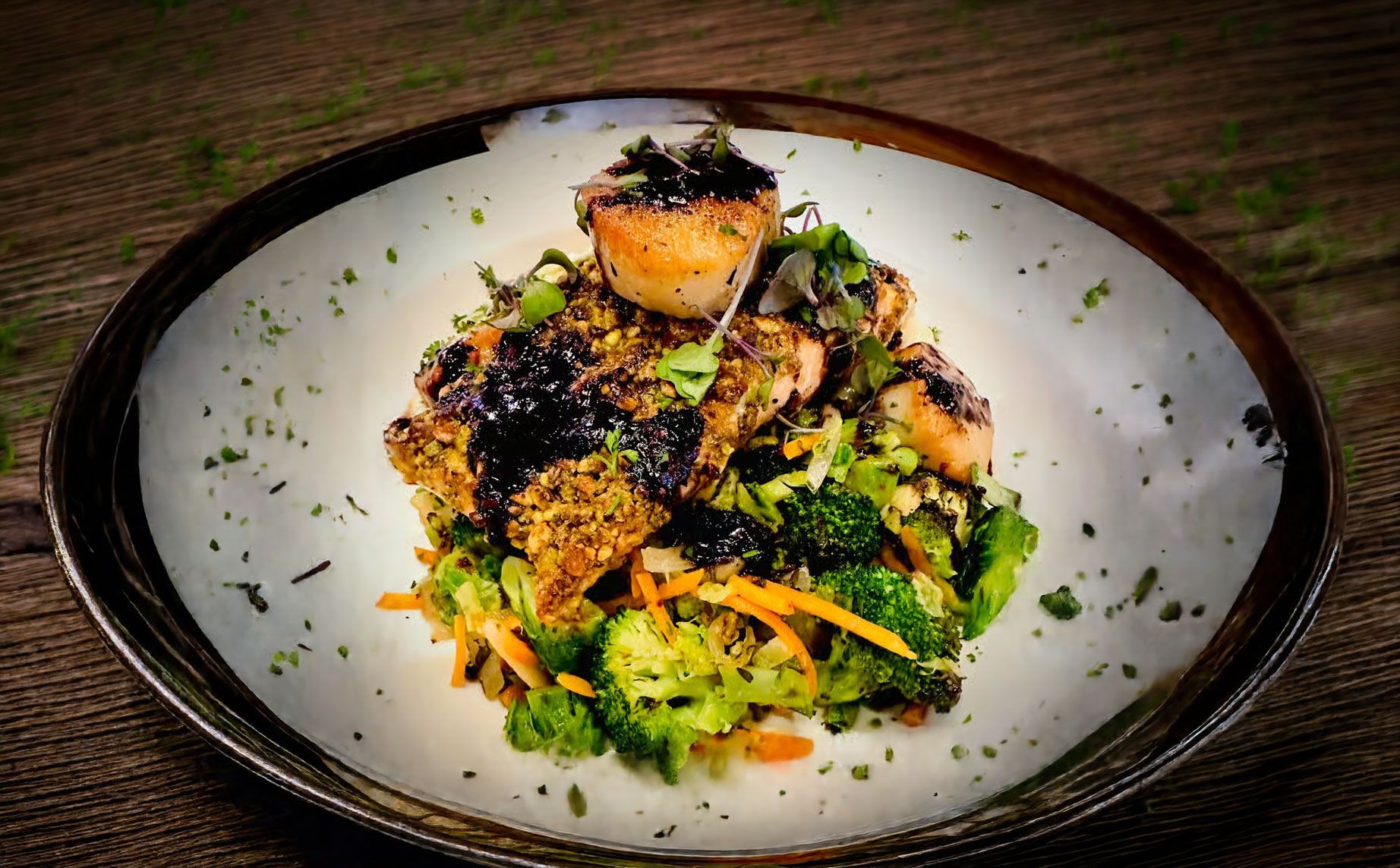 Plated gourmet salad with grilled vegetables, herbs, and a charred topping on a white plate