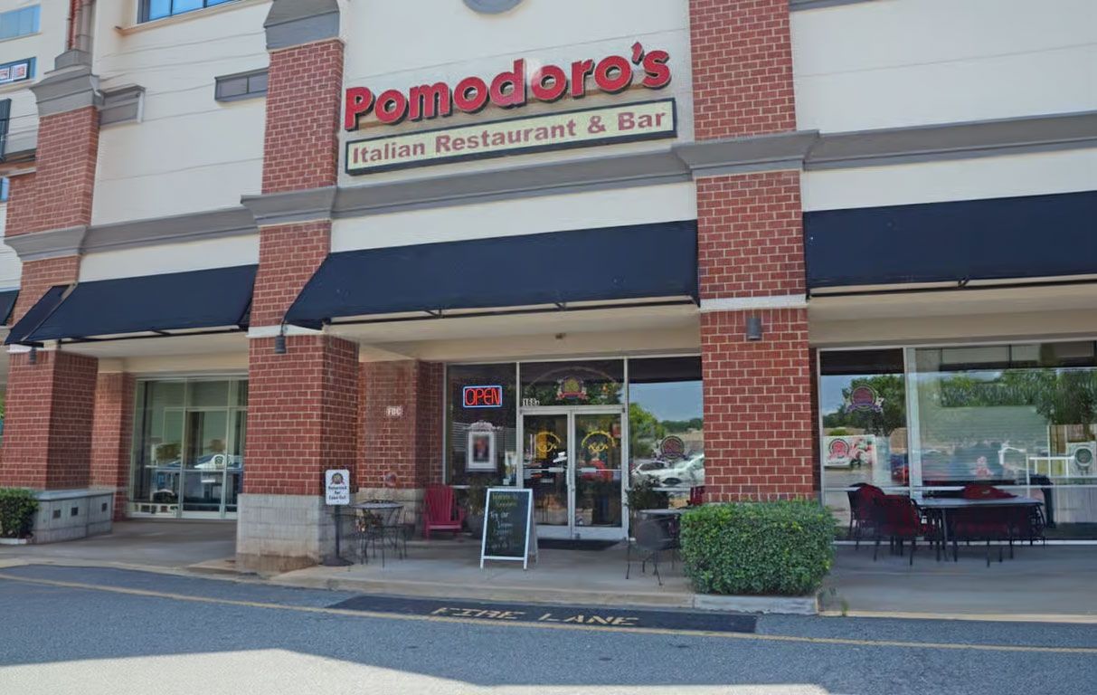 Pomodoro’s storefront with a brick facade, blue awnings, and a glass entrance in a strip mall.