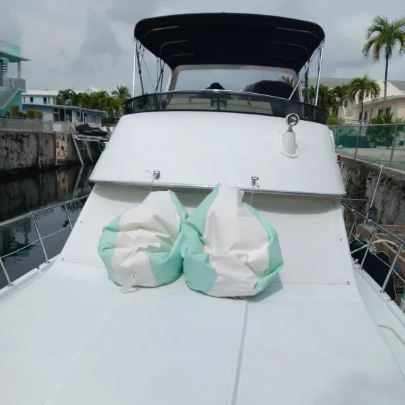 Rear view of a white boat with two mint green bean bag chairs on the deck, in a canal.