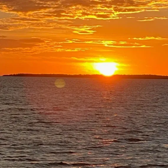 Sunset over water with a bright orange sky.