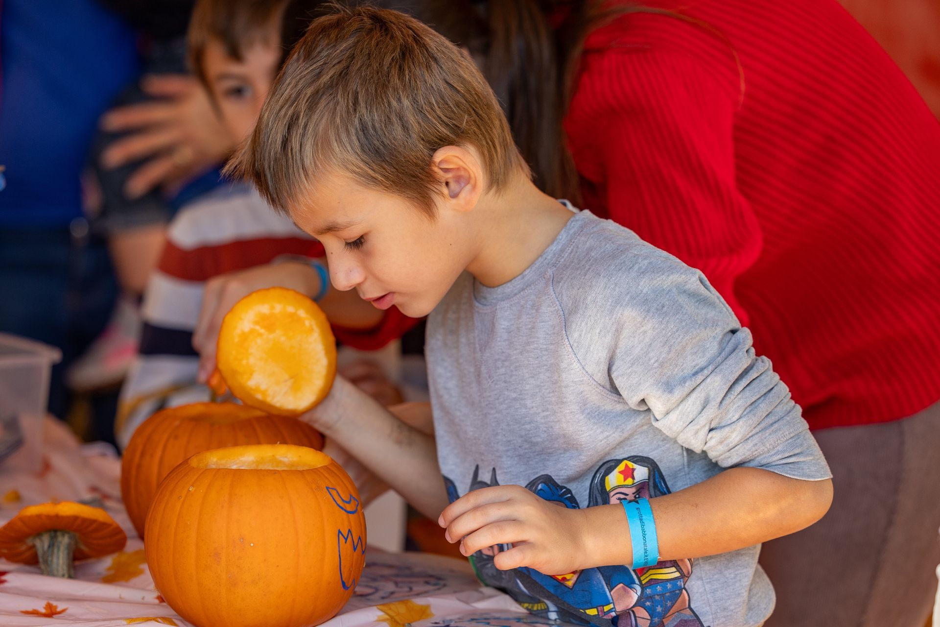 Un ragazzino sta intagliando una zucca seduto a un tavolo.