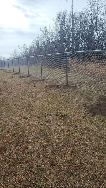 There is a chain link fence in the middle of a field.