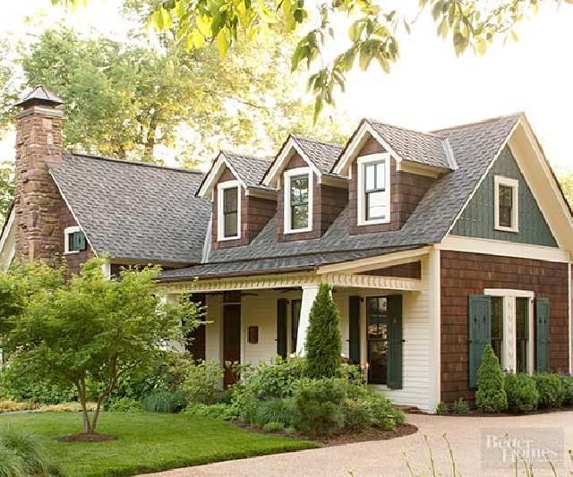 Cottage-style home with brown shingle siding, green shutters, and three dormers with white trim.
