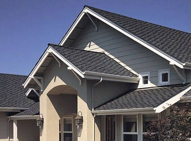 Beige house with dark gray shingle roof, white trim, and a clear blue sky.