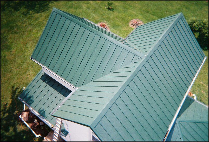 Green metal roof on a house, angled overhead shot.
