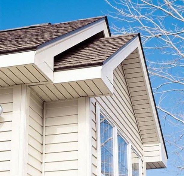 Beige siding and white trim on a house with brown shingle roof, under a blue sky.