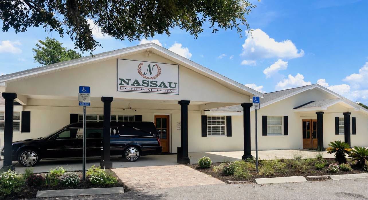 Exterior of Nassau orthopedic clinic with parked SUV, white columns, and clear blue sky
