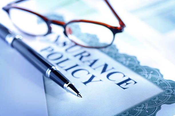 A pen and glasses sit on top of an insurance policy