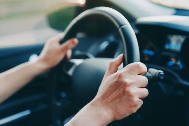 A person is driving a car with their hands on the steering wheel.