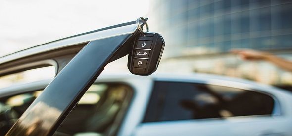 A car key is hanging from the side of a car.