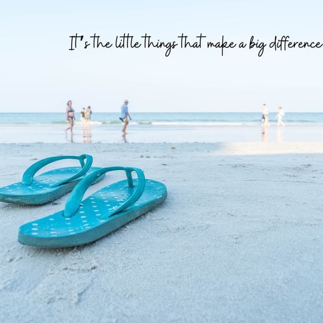 Blue flip-flops on a sandy beach with people walking by the shoreline and the text “The little things that make a big difference.”