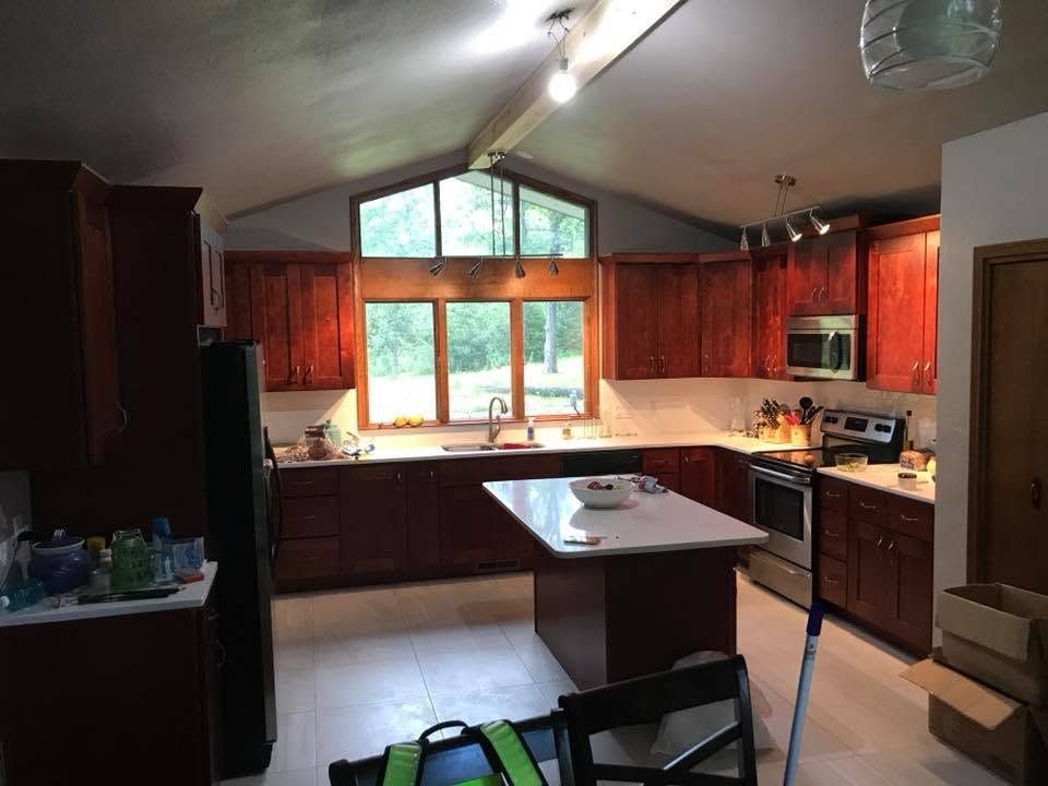 Bright empty modern room with wood floors, recessed lights, and a large window.