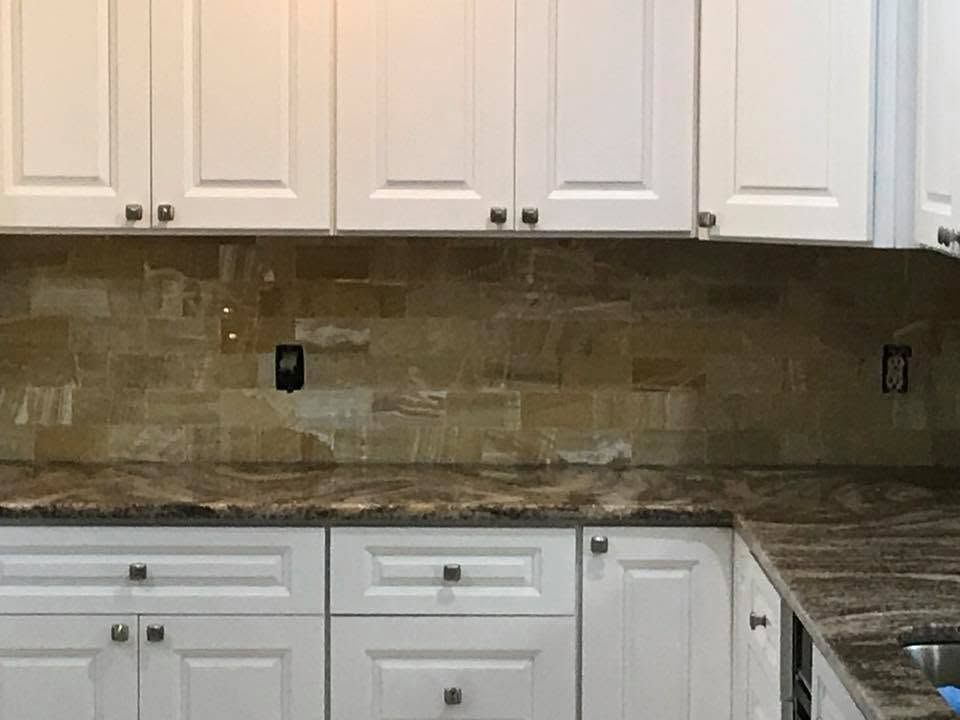 White kitchen cabinets with under-cabinet lighting and a tiled backsplash.