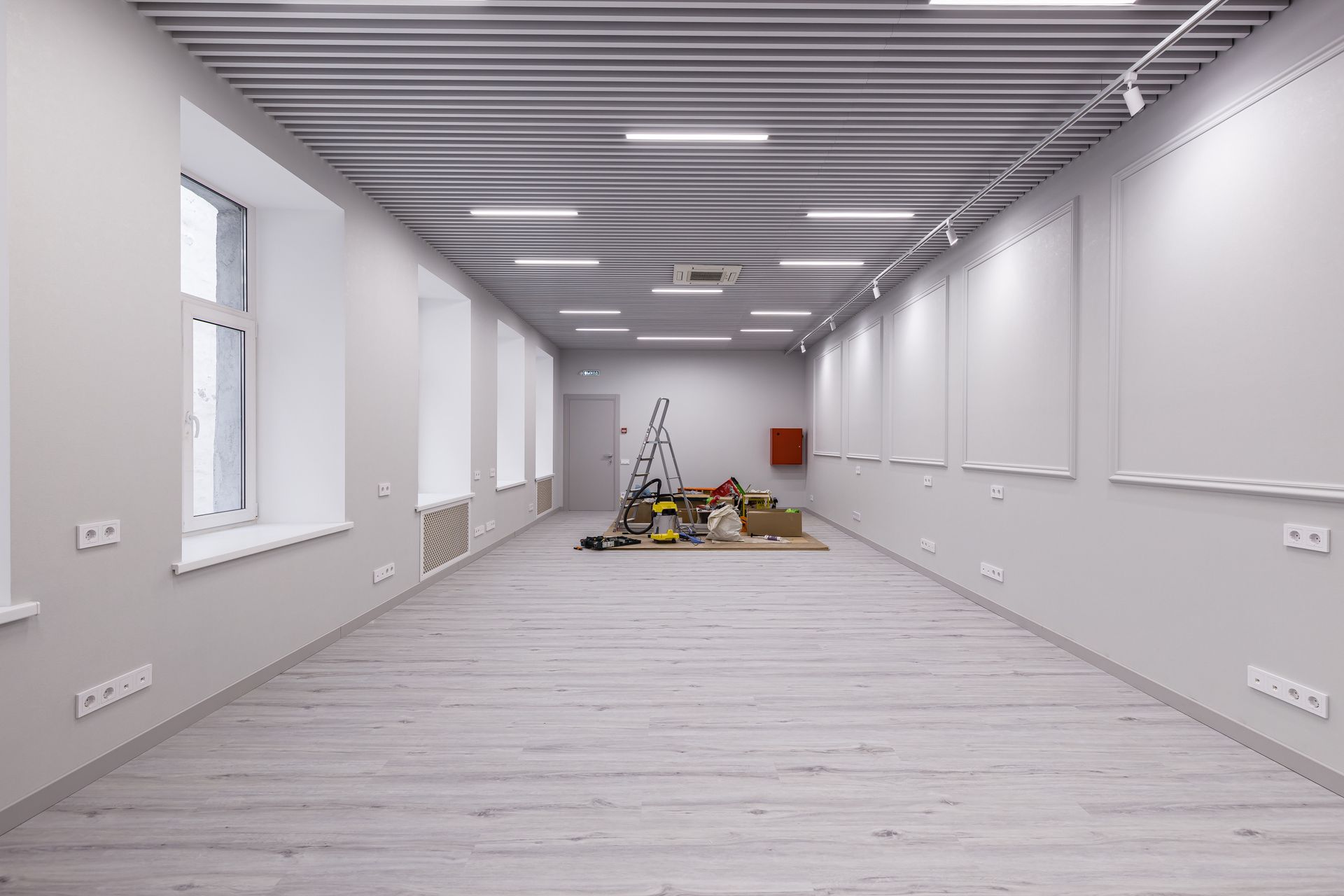 Empty white room with a ladder and tools, showing ongoing interior renovation.